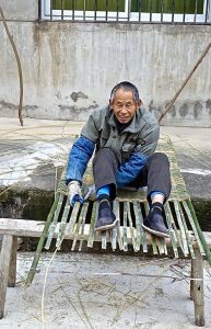 Li Meng Wenweaving a mat outside his home. Credit: Kalinga Seneviratne