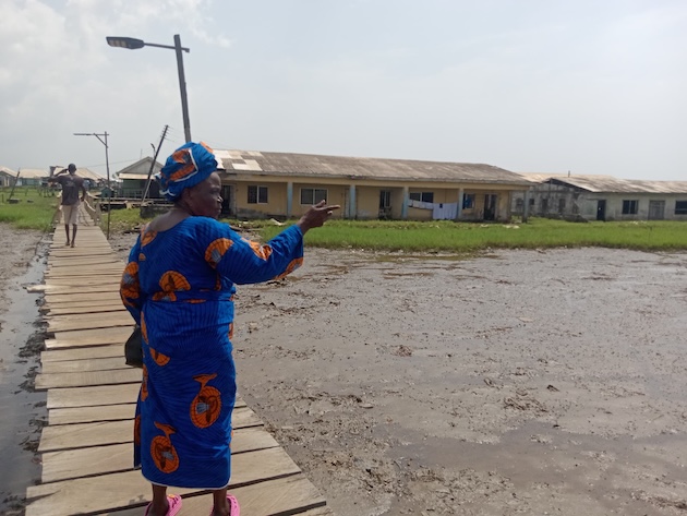 Ayetoro resident Akinwuwa Omobolanle gestures towards a swampy expanse, a result of recurrent floods. Credit: Promise Eze/IPS