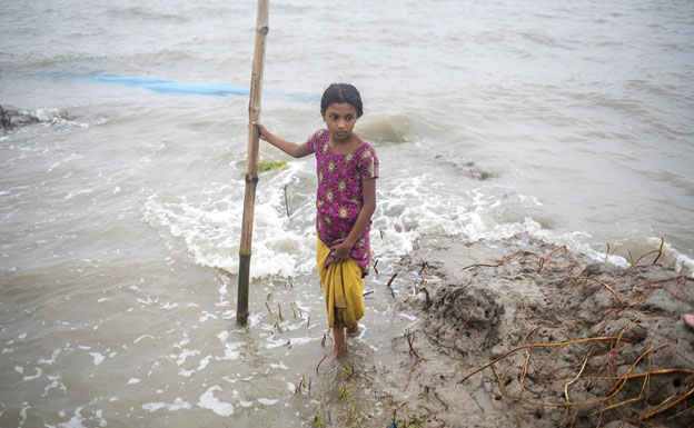 A young girl trying to cross a flooded road in Bangladesh following the wake of Cyclone Remal. Bangladesh is one of the world’s most climate-sensitive nations and is expected to be significantly impacted by rising global temperatures. Credit: UNICEF/Farhana Satu