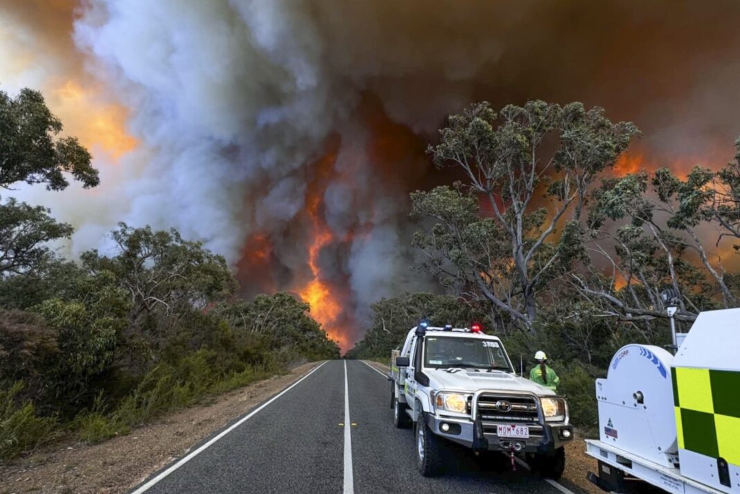 In this photo released by the State Control Centre, Country Fire Authority personnel watch as smoke billows from an out of control bushfire in the Grampians National park, in Victoria state, Australia, Friday, Dec. 20, 2024. (State Control Centre via AP)