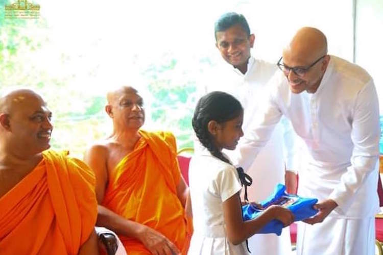 Photo: Malalasekera Foundation chairman Ashan Malalasekera presenting schoolbooks to a student at a function in Kataragama recently. Credit: Manoj Divithuragama.