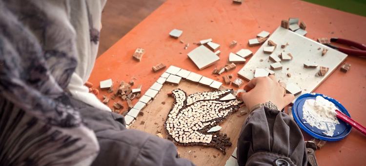 Photo: A woman crafts a mosaic depicting a peace dove in the Za’atari refugee camp in Jordan. © UN Women/Christopher Herwi