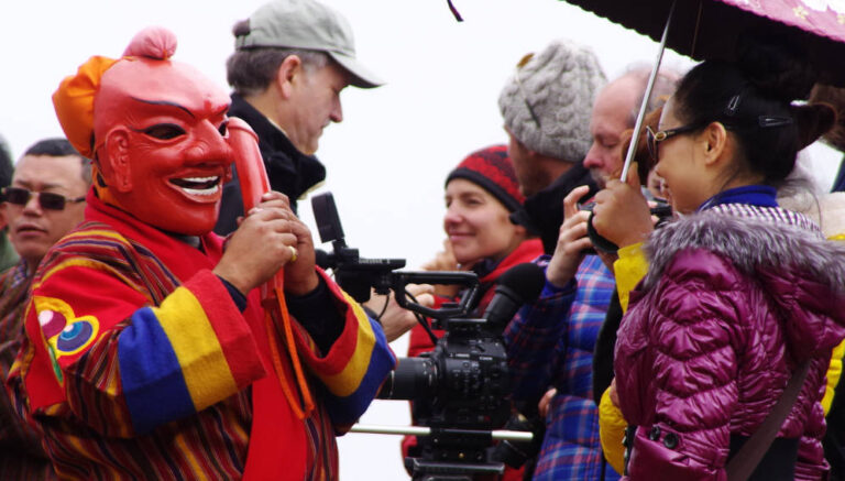 A local artist entertaining tourists and a filming crew in Bhutan. According to the UN World Tourism Organization (UNWTO), the global tourist industry was among the hardest hit by the COVID-19 pandemic. Copyright: Courtesy of Tourism Council of Bhutan (CC BY-ND 2.0).