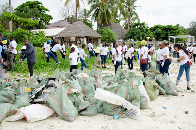 A group of employees from Tanzania Standard Chartered Bank remove plastic waste at Coco Beach in Dar es Salaam as part of the bank's social corporate responsibility initiative. Credit: Kizito Makoye/IPS