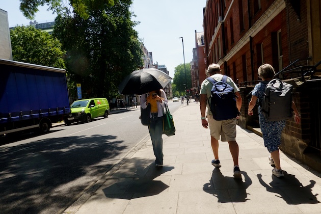 A person uses an umbrella to keep cool during a heatwave in London, England, in June 2026. Credit: Alastair Johnstone-Hack / Climate Visuals