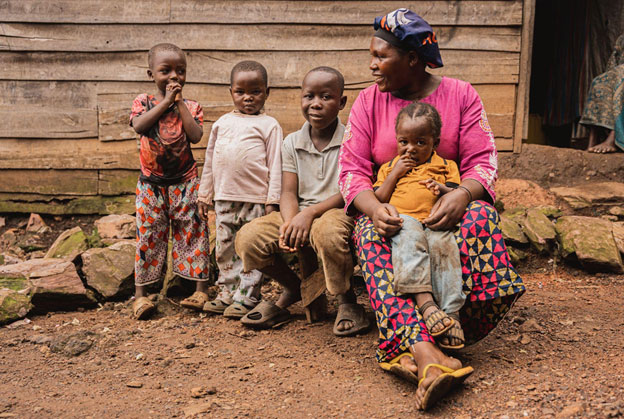 Mwavita Rohomoya sits with her four children in front of her drink stall in Minova, Kalehe territory, South Kivu province, DR Congo, on 23 April 2025. Minova is one of the first areas in South Kivu to be affected by the resurgence of violence, one of the immediate consequences was the rise in prices of staple foods and essential goods. UNICEF’s cash transfer programme helped families meet their urgent needs—buying food, finding shelter, and accessing healthcare—while also enabling some, like Mwavita, to invest in small-scale income-generating activities. Credit: UNICEF/Christian Mirindi Johnson